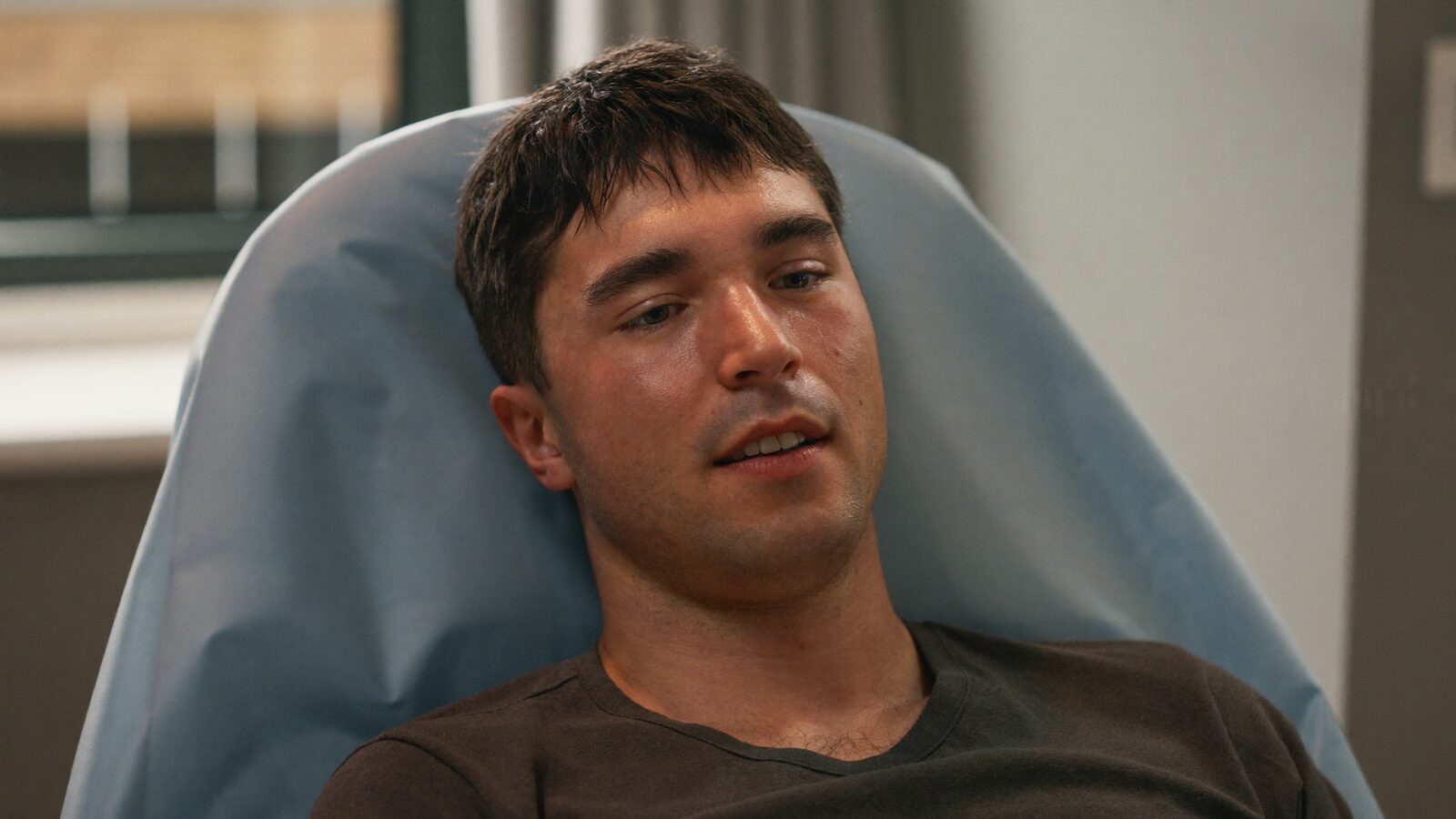Calm man in his 30s with short hair sitting in a reclined treatment chair with a relaxed expression in soft clinical light