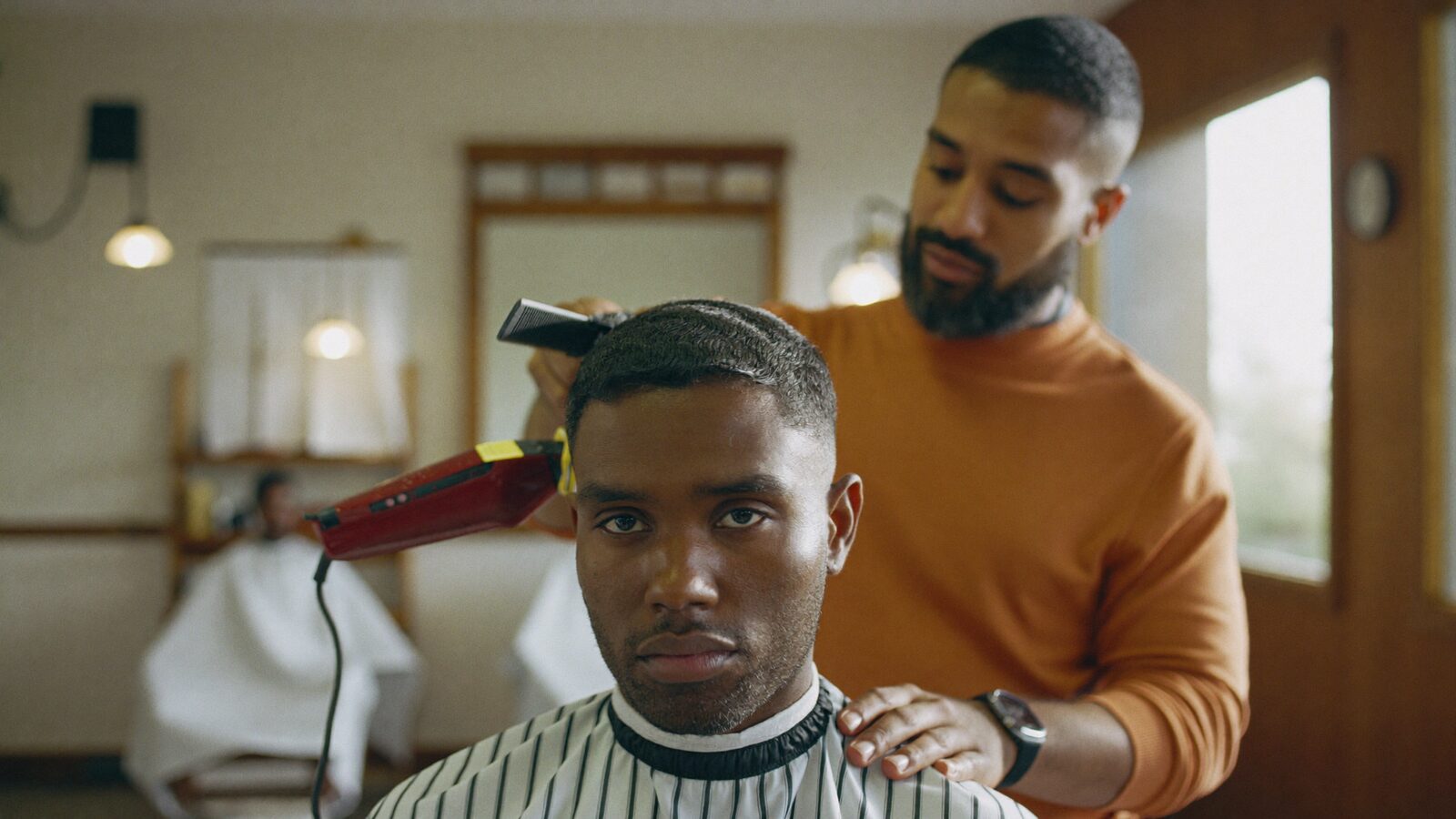 Barber giving a man in his 30s a clean fade haircut in a stylish Miami barbershop